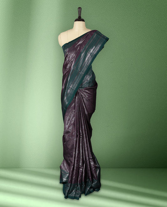 Deep Grape colour semi silk saree featuring neem zari floral kodi motifs all over the body, complemented by a rich green woven border with geometric detailing, with matching blouse.