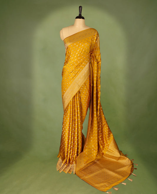 Mustard Gold  semi-Banaras satin crepe saree featuring traditional closely woven buttas on the body, complemented by an antique-style border and a matching self-coloured blouse.