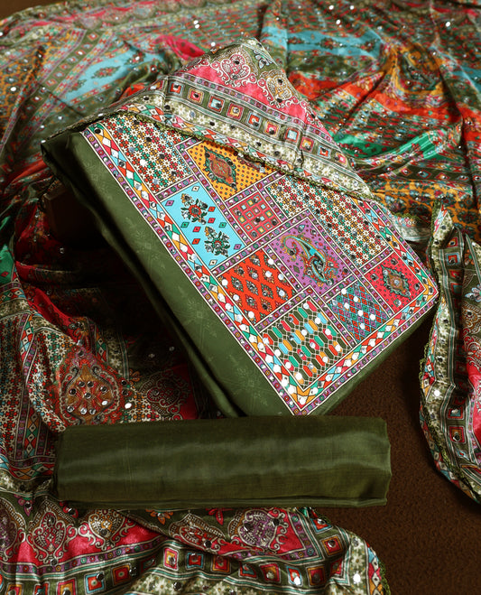 Elegant olive green churidhar material with vibrant multicolour geometric and paisley prints, enhanced with delicate mirror work, paired with a plain matching bottom and bold printed dupatta, perfect for festive occasions.