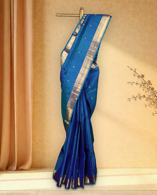 Peacock blue colour pure Kancheepuram saree with gold zari symmetrical motifs, traditional border with peacock and chakra designs, grand pallu with diamond motifs, and matching blouse.