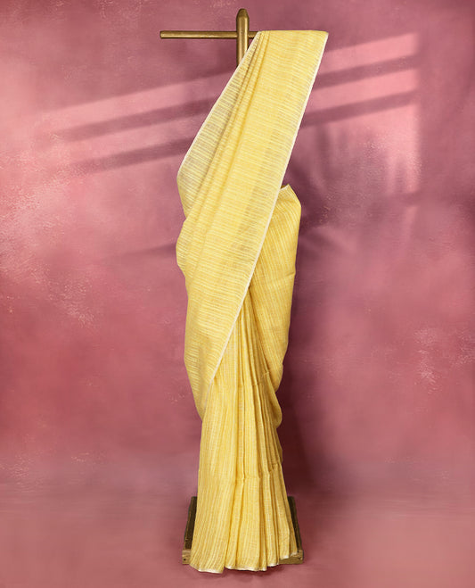 Pastel yellow colour pure linen saree adorned with delicate stripe patterns all over the body, highlighted with a simple white border and comes with a matching blouse