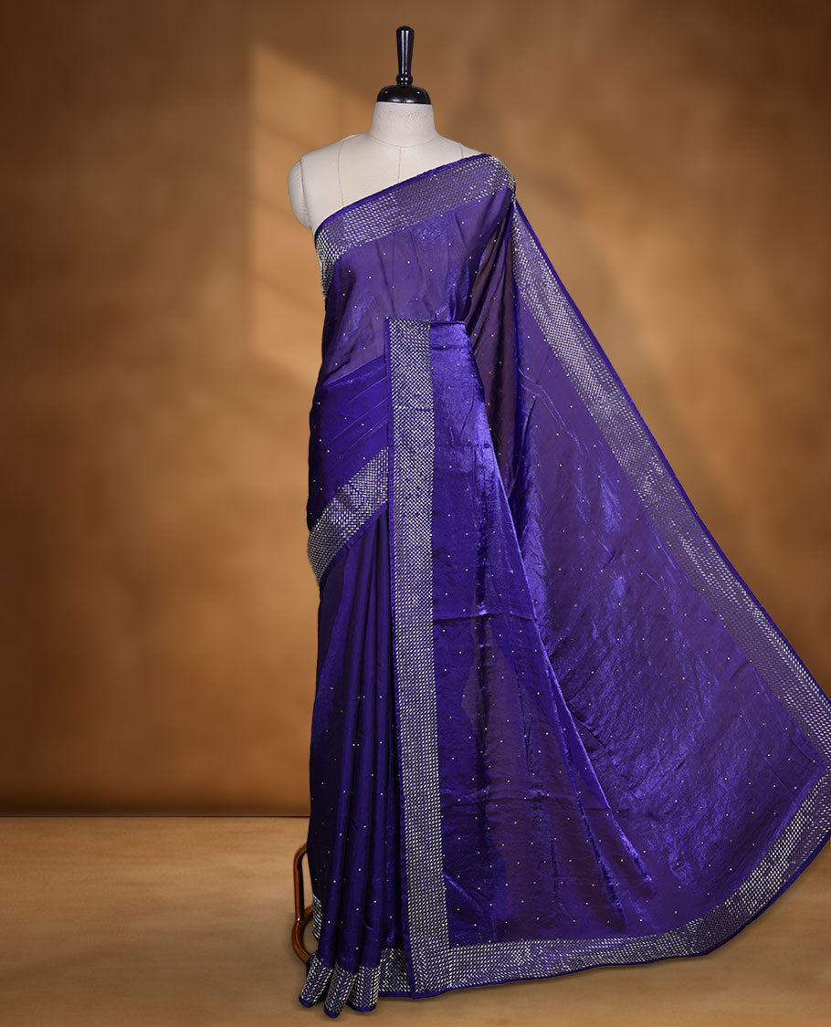 Dark violet colour chiffon designer saree, featuring dainty scattered stones on the body, enriched with dense stone work and a heavy metallic stone border and pallu, paired with a matching blouse.