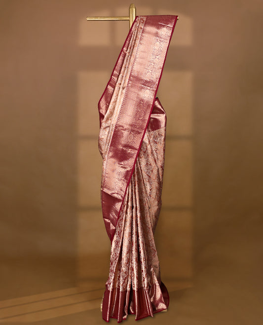 Pastel maroon Colour Kancheepuram tissue silk saree adorned with intricate silver floral zari work on the body, beautifully highlighted by a maroon traditional Rudraksham and floral design border, and paired with a matching blouse.