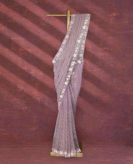 Lavender colour net designer saree featuring crisscross cut beads detailing on the body, adorned with beads and sequin worked floral kodi scallop border, paired with a matching worked blouse