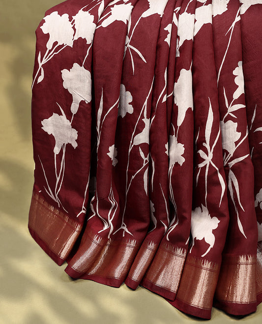Maroon colour Viscos semi printed saree featuring a golden zari border, white floral printed motifs across the body, and comes with a matching blouse