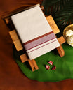 Off white cotton single dhoti featuring a maroon kara highlighted with golden zari edging and fine double lines, blending tradition with elegance, perfect for rituals, festive occasions, and cultural gatherings.