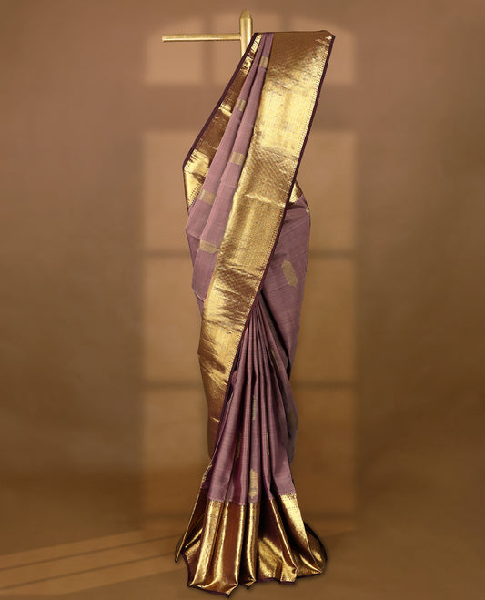 Muted mauve Colour traditional Kancheepuram silk saree adorned with antique zari traditional motifs on the body, featuring a contrasting border with Rich floral and geometric patterns, and paired with a matching blouse.
