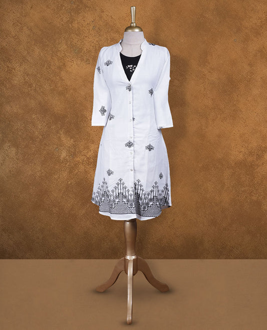 White embroidered shirt dress with band collar, contrast black inner layer at neckline, front button placket, three-quarter sleeves, and intricate black border embroidery at hem