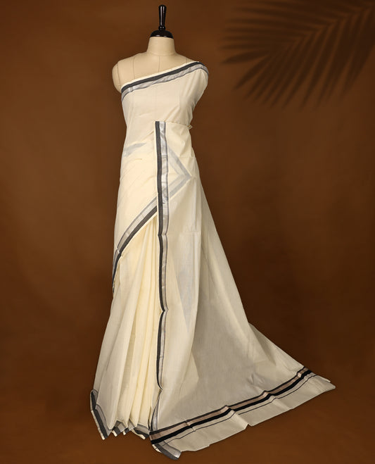 Elegant off white colour Kerala cotton saree with silver and black dual tone borders, Soft, breathable, and paired with a matching blouse, it’s perfect for festive occasions, office wear, or elegant day outings.
