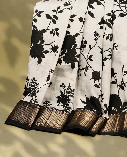 Off white colour viscose semi printed saree featuring a golden zari border, bold black floral vine prints across the body, and comes with a matching blouse