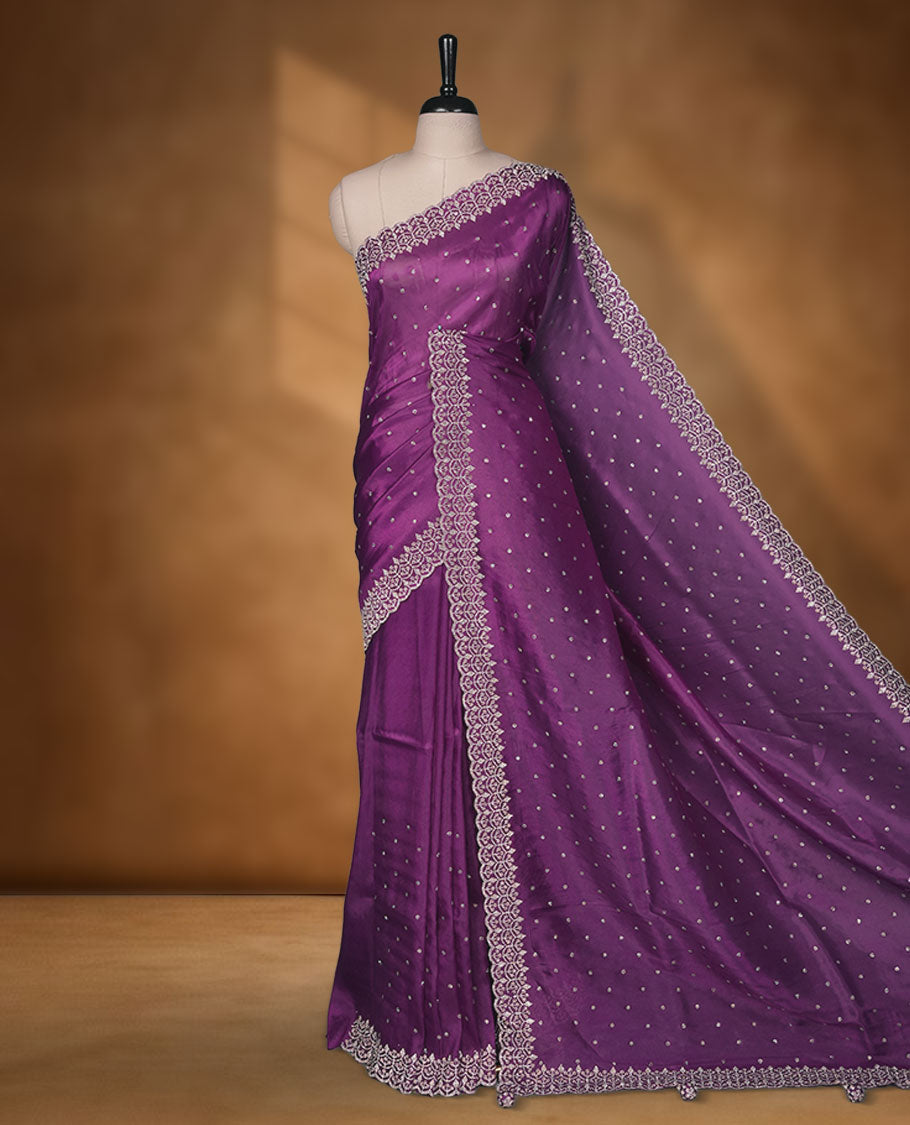 Purple Colour shimmer fancy saree adorned with scattered white stone buttas all over the body, paired with a delicate stone worked border and matching blouse featuring floral vine stone embroidery