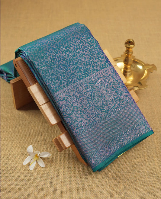 Peacock blue colour Kanchipuram pattern Manthrakodi saree featuring geometrical design antique copper zari floral pencil art jacquard design across the body, traditional mango & diamond designs on border, and self zari blouse piece.