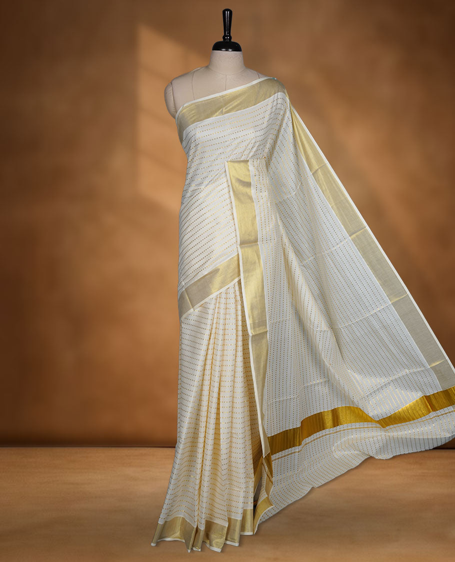 Off white colour cotton Kerala saree featuring fine dotted zari lines on the body, complemented by a classic golden zari border and traditional pallu, paired with a matching blouse.