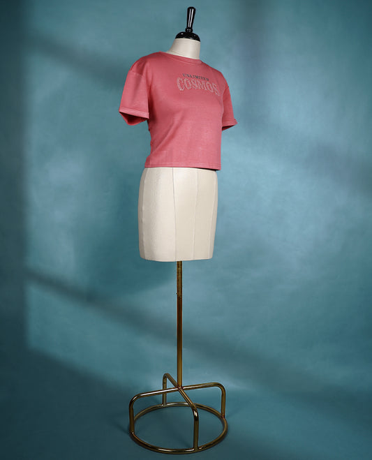 Rose pink cropped T shirt with short sleeves and rolled cuffs, featuring a subtle shimmer design on the front.