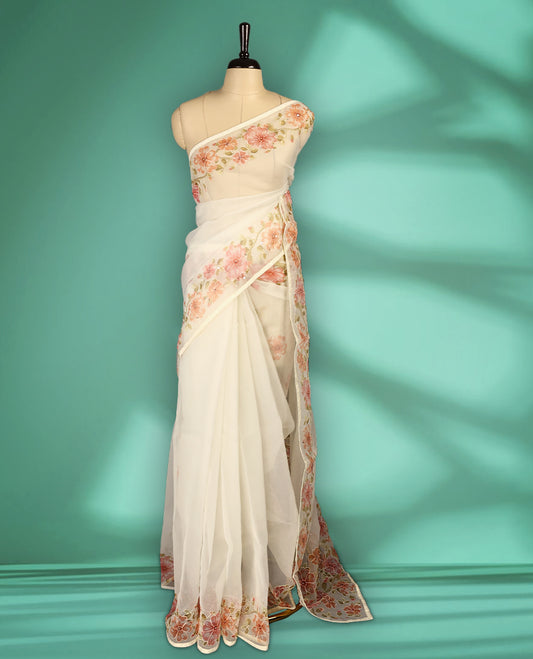 Ivory white colour organza saree adorned with Peach floral print with thread detailing on the border and pallu, in a sheer finish that adds elegance, paired with a matching blouse for a graceful look.