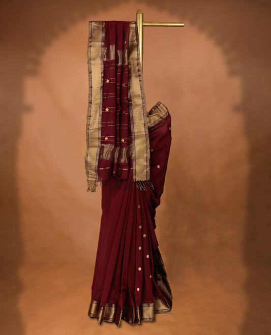 Maroon coloured Maheshwari Cotton saree featuring antique Zari Round motifs across the entire body, complemented by a traditional gold coloured border and a matching blouse.
