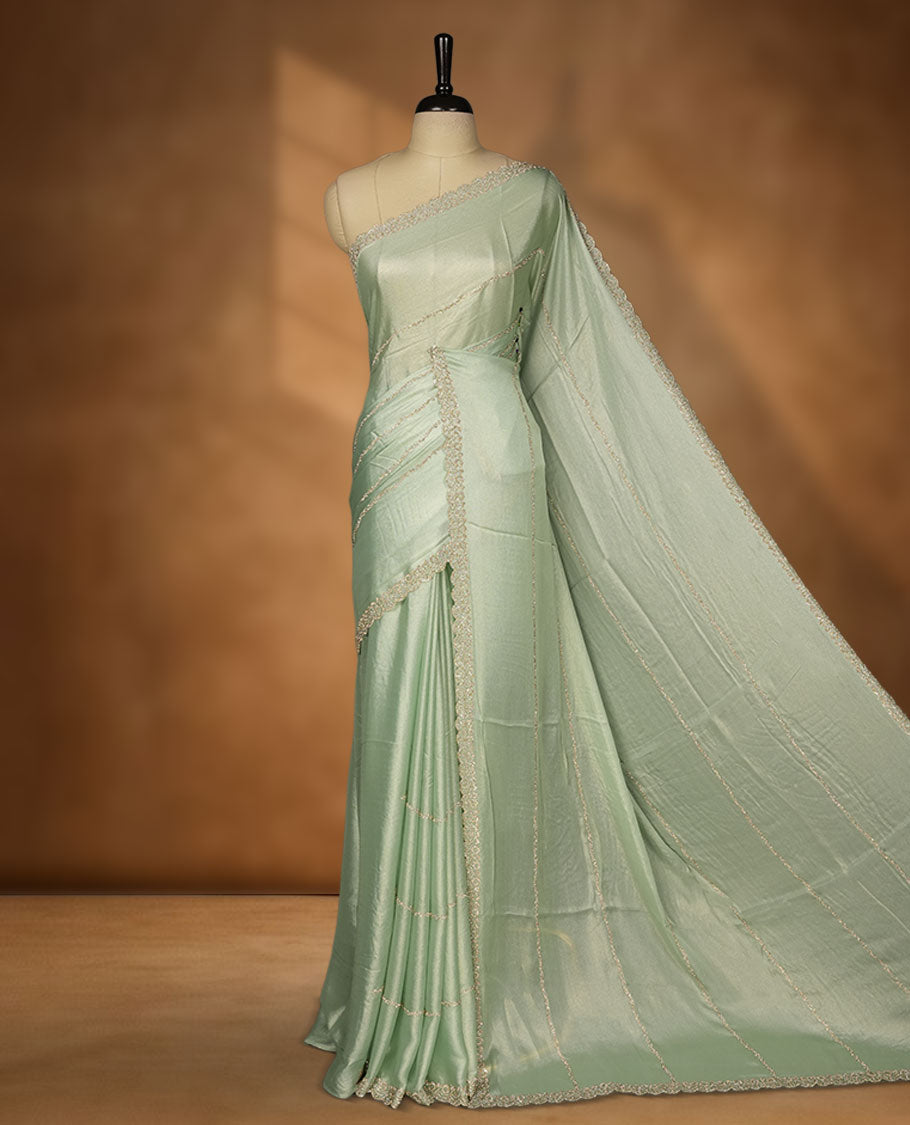 Pastel Green colour net shimmer fancy saree adorned with white stone buttas, paired with a delicate stone worked border and matching blouse.