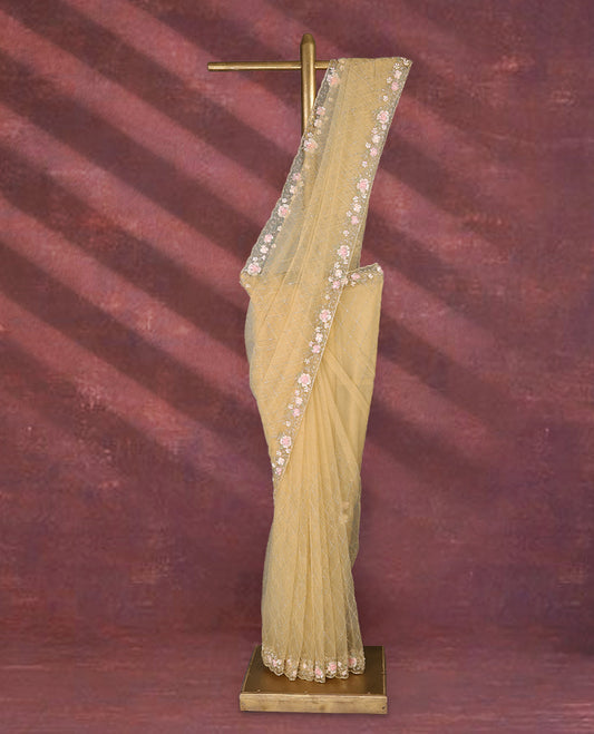 Pastel yellow colour net designer saree featuring crisscross cut beads detailing on the body, adorned with beads and sequin worked floral kodi scallop border, paired with a matching worked blouse