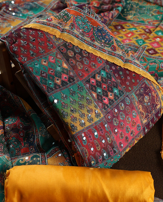 Yellow colour churidhar material with vibrant multicolour geometric and paisley prints, enhanced with delicate mirror work, paired with a plain matching bottom and bold printed dupatta, perfect for festive occasions.