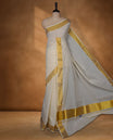 Off-white colour cotton Kerala saree crafted in a soft, sheer weave, finished with a rich gold kasavu border along the body and pallu, and paired with a matching blouse. (Copy)