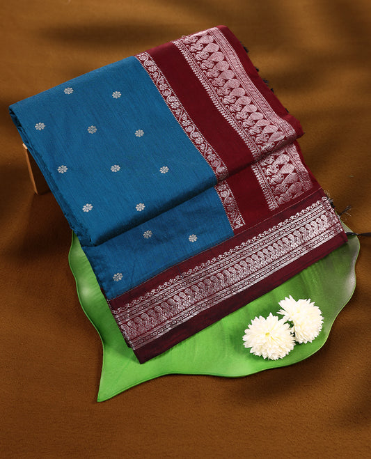 Blue colour mixed Kalyani cotton saree featuring Silver zari flower motifs throughout the body, paired with a Maroon colour traditional border and pallu, with matching blouse
