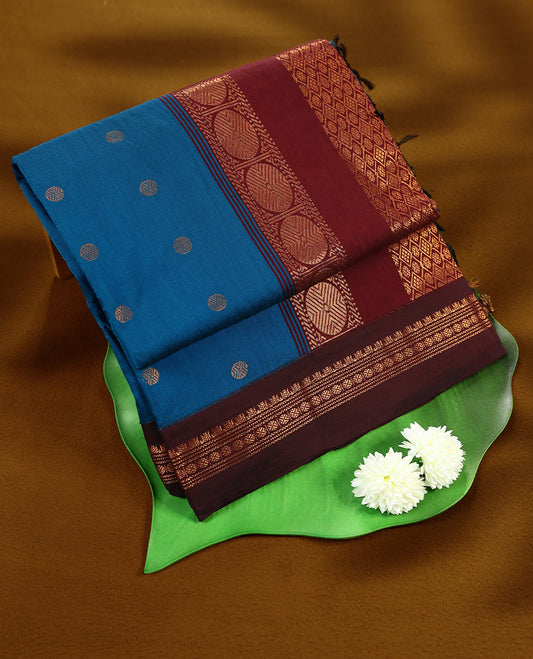 Blue colour mixed Kalyani cotton saree featuring Copper zari Bindi motifs throughout the body, paired with Maroon colour traditional border and pallu, with matching blouse