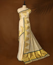 Elegant off white colour pure handloom soft tissue saree with golden zari detailing and green edging, Sheer, lightweight, and lustrous & paired with a matching blouse, perfect for weddings and festive occasions.