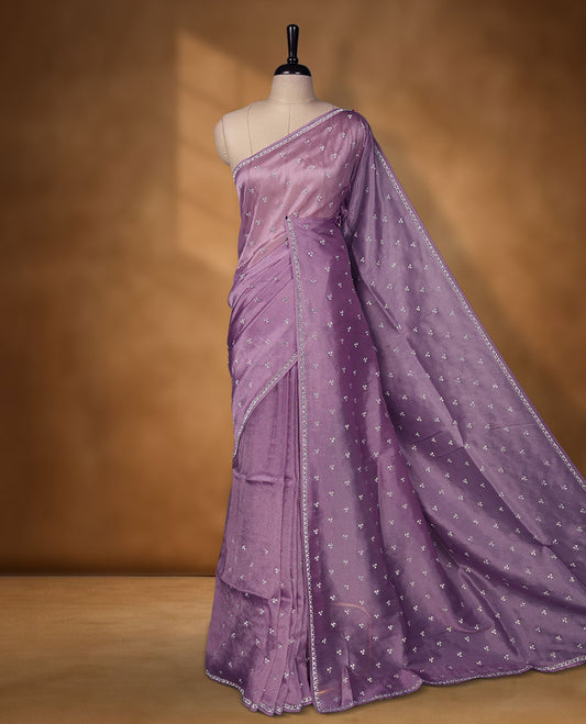 Lavender Colour net shimmer fancy saree adorned with scattered white stone buttas all over the body, paired with a delicate stone worked border and matching blouse.