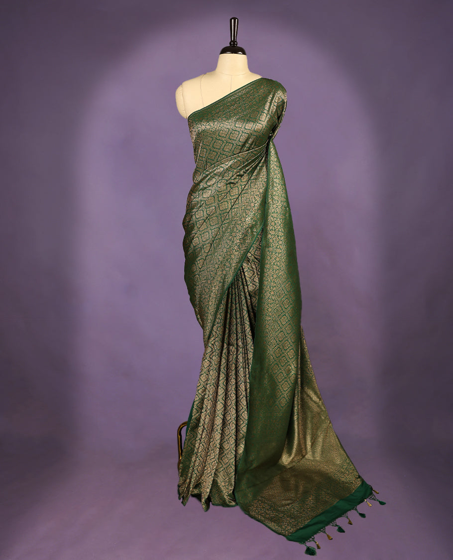 Green colour semi Banaras Katan saree featuring an antique Gold zari jacquard body, complemented by a self colour traditional border with a floral kodi design, paired with a matching blouse