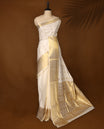 Elegant off white colour cotton Kerala saree with golden buttas, rich zari border, and intricately woven pallu featuring floral and temple motifs. Perfect for festive occasions, paired with a matching blouse.