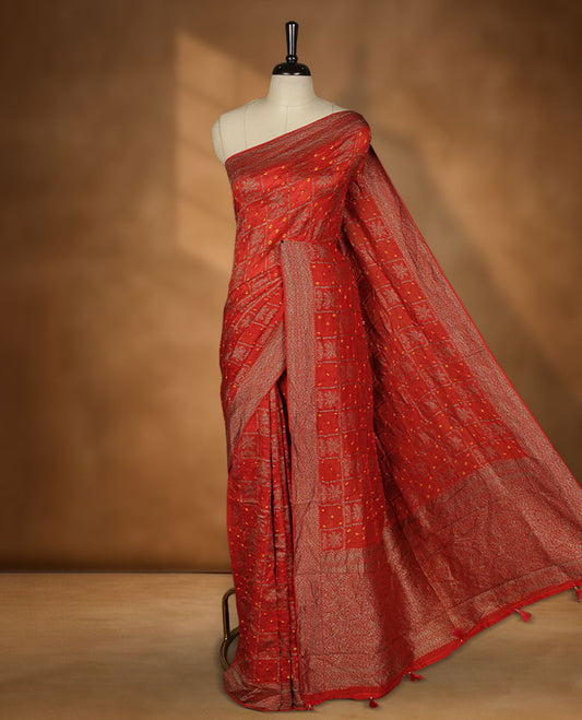 Reddish orange colour Banarasi Bandhani silk saree featuring with intricate Banarasi motifs on body, complemented by antique zari woven border and grand pallu, paired with matching  blouse