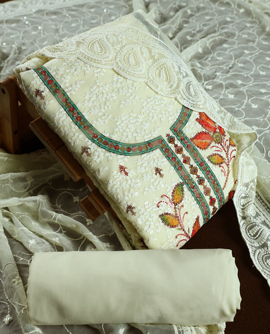 Cream colour churidhar material with embroidered green colour neck work, white thread floral motifs on the body, and multicolor floral detailing in orange, yellow & green, Comes with plain bottom and embroidered dupatta.