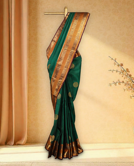 Bottle green pure Kancheepuram saree with gold zari Mayoora Chakra and diamond motifs on the body, contrast brown Kalakshetra border, grand pallu, and matching blouse.