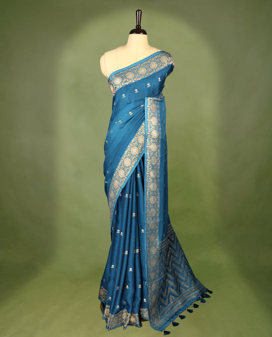 Blue colour pure Banaras crepe saree showcases elegant silver zari Flower Motifs all over the body, a traditional Banarasi gold zari border, a rich intricately woven pallu, and comes with a matching blouse.