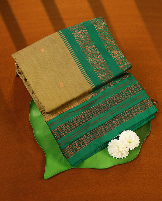 Warm olive and Green Kalyani cotton saree adorned with delicate woven buttas on the body, complemented by intricate zari woven border and pallu in green, paired with a matching blouse
