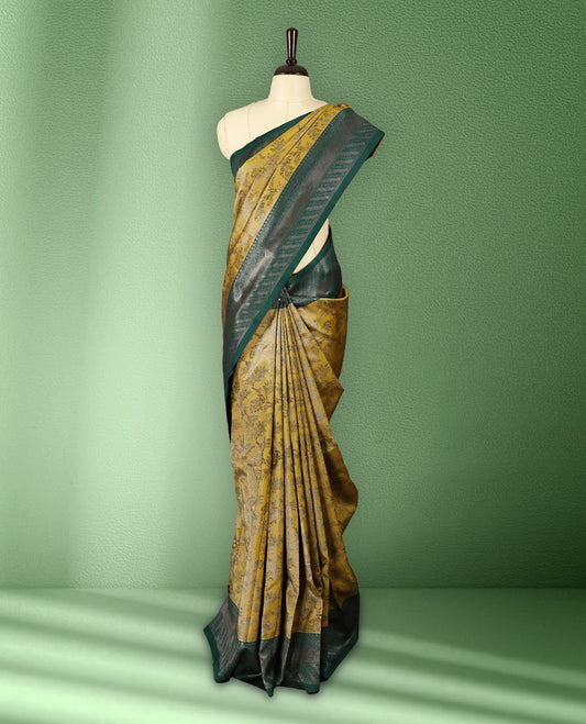 Deep Mustard colour semi silk saree featuring neem zari floral kodi motifs all over the body, complemented by a rich green woven border with geometric detailing, with matching blouse.