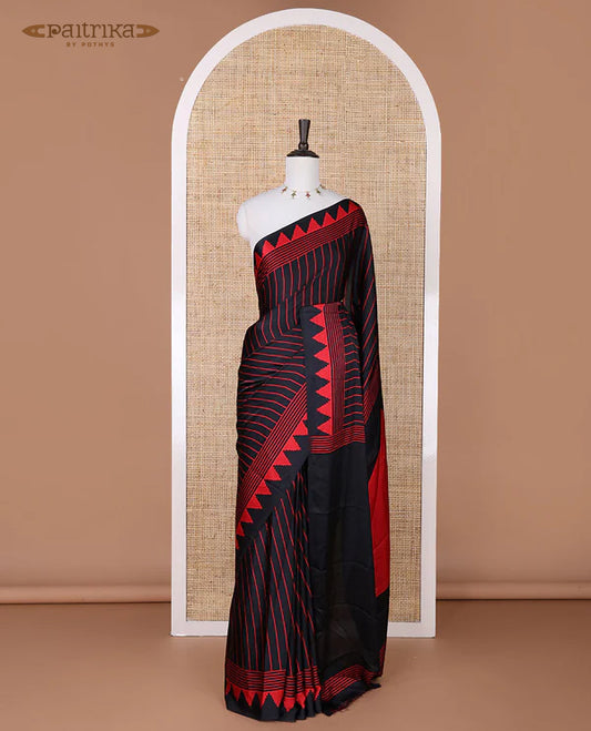 Black sem imodal crepe saree adorned with red vertical line prints, complemented by a temple border and circle butta design on the pallu, paired with a matching printed blouse.