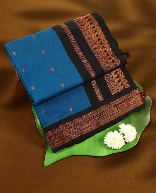 Blue colour mixed Kalyani cotton saree featuring Copper zari motifs throughout the body, paired with a Black colour traditional border and pallu, with matching blouse