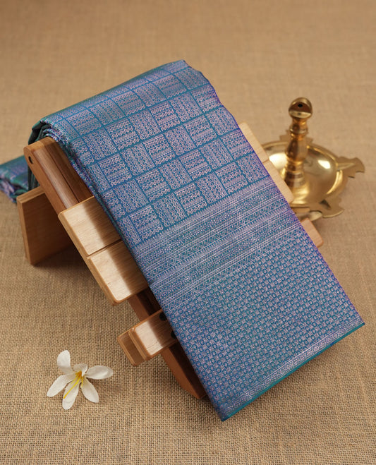 Peacock blue colour Kanchipuram pattern Manthrakodi saree featuring intricate geometric antique copper zari brocade design across the body, beautifully complemented with a matching self brocade blouse piece.