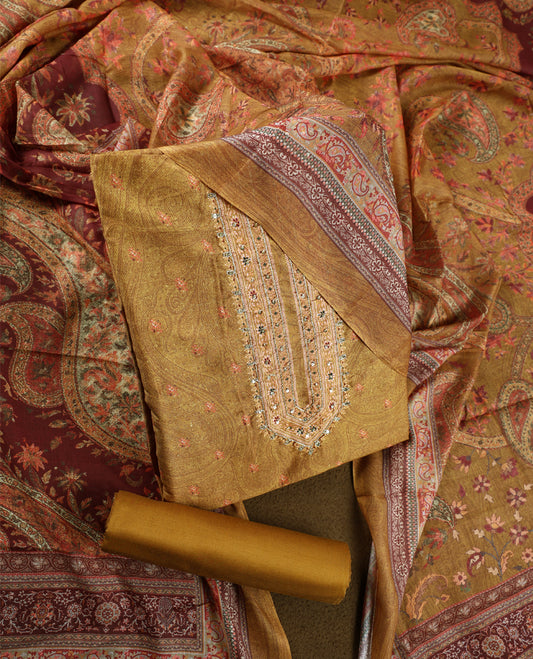 Dark ochre yellow colour churidhar material featuring intricate paisley prints and delicate embroidery with stone highlights, paired with a plain matching bottom and a printed dupatta.