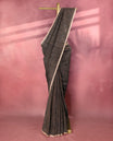 Black colour pure linen saree featuring fine beige thread stripes running throughout the body, accented with a soft beige border and pairs gracefully with a matching blouse.