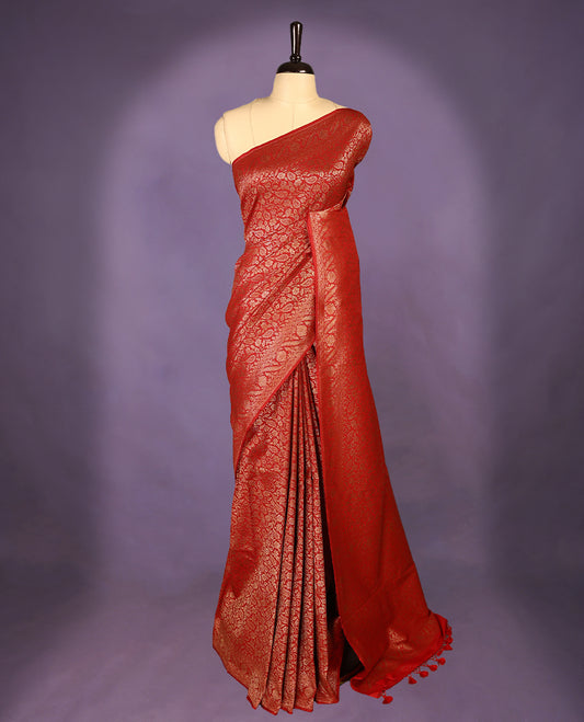 Chilli red colour semi Banaras Katan silk saree featuring intricate Antique Bronze zari floral and vine patterns woven throughout the body, enhanced with a rich traditional border and detailed pallu, paired with a matching blouse piece.