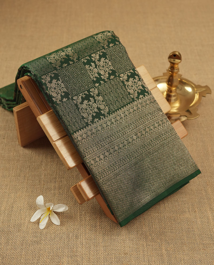 Bottle green colour Kanchipuram pattern Manthrakodi saree featuring intricate geometrical design and turning border in antique gold zari jacquard, crafted in rich Kanchipuram silk, paired with a matching jacquard blouse piece.