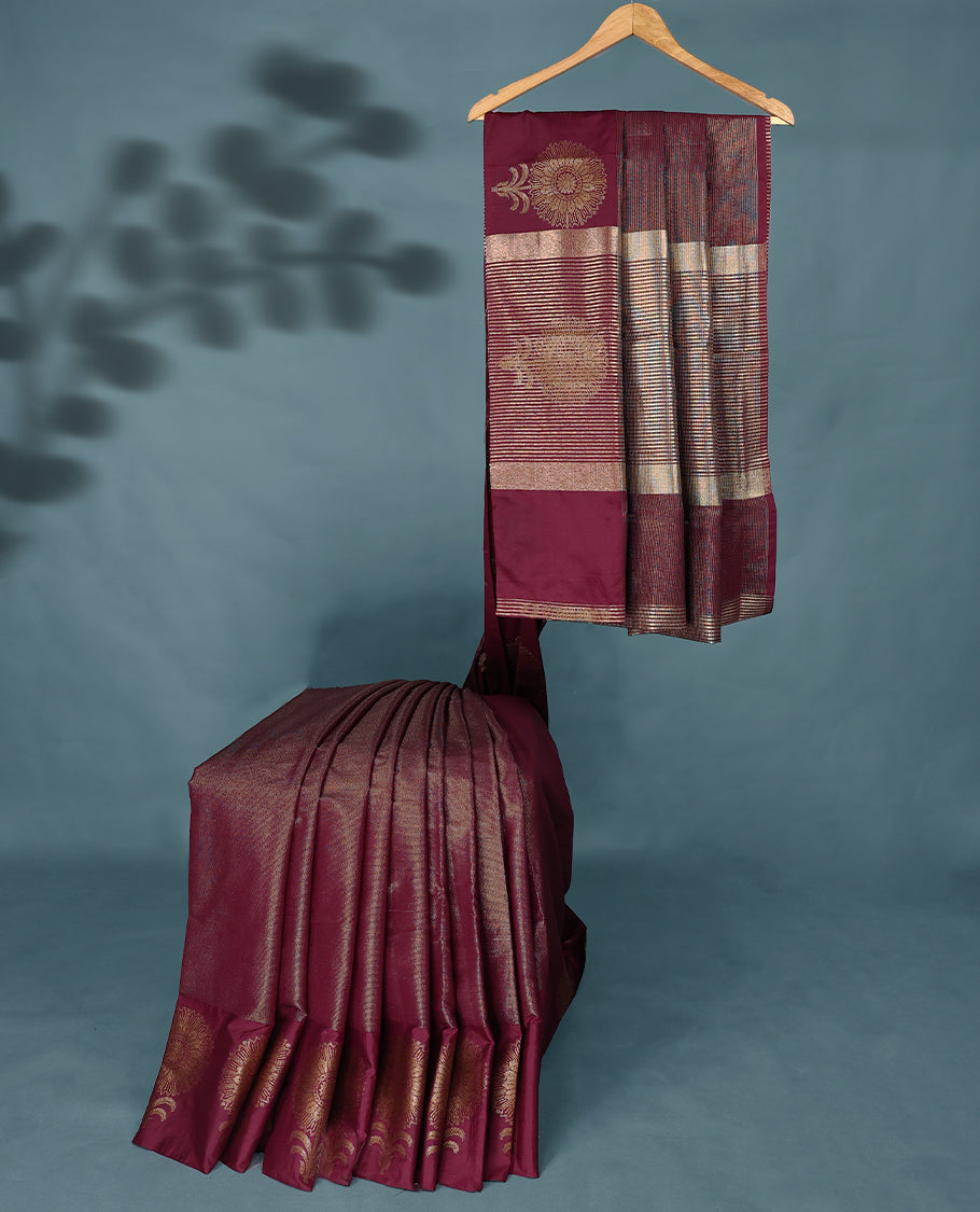 Dark Maroon Colour Semi Tussar Silk saree featuring golden zari horizontal lines across the body, adorned with bold floral motifs on the border, paired with a matching blouse.