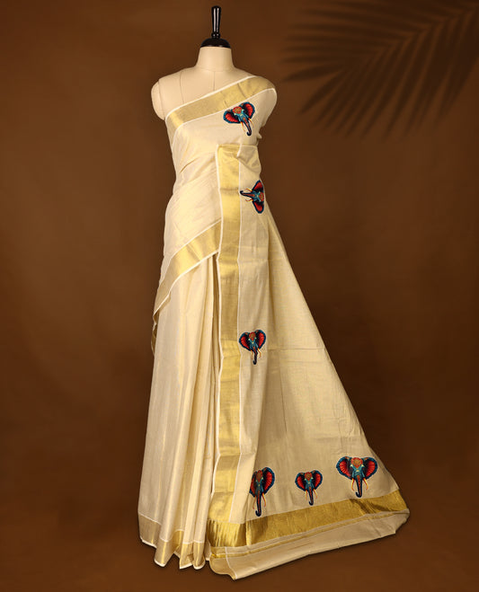 Light Gold colour Tissue Kerala saree featuring Elephant prints on body and a beautifully woven Gold Kasavu border, paired with a matching blouse perfect for festive occasions.