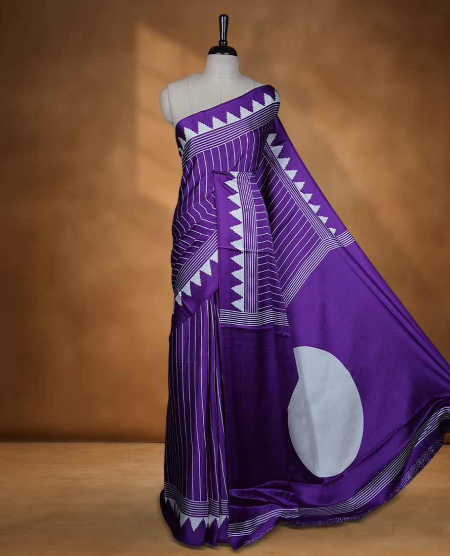 Violet colour semi modal saree featuring white colour geometric borders and fine stripe detailing, finished with an oversized circular motif on the pallu, paired with a matching printed blouse.