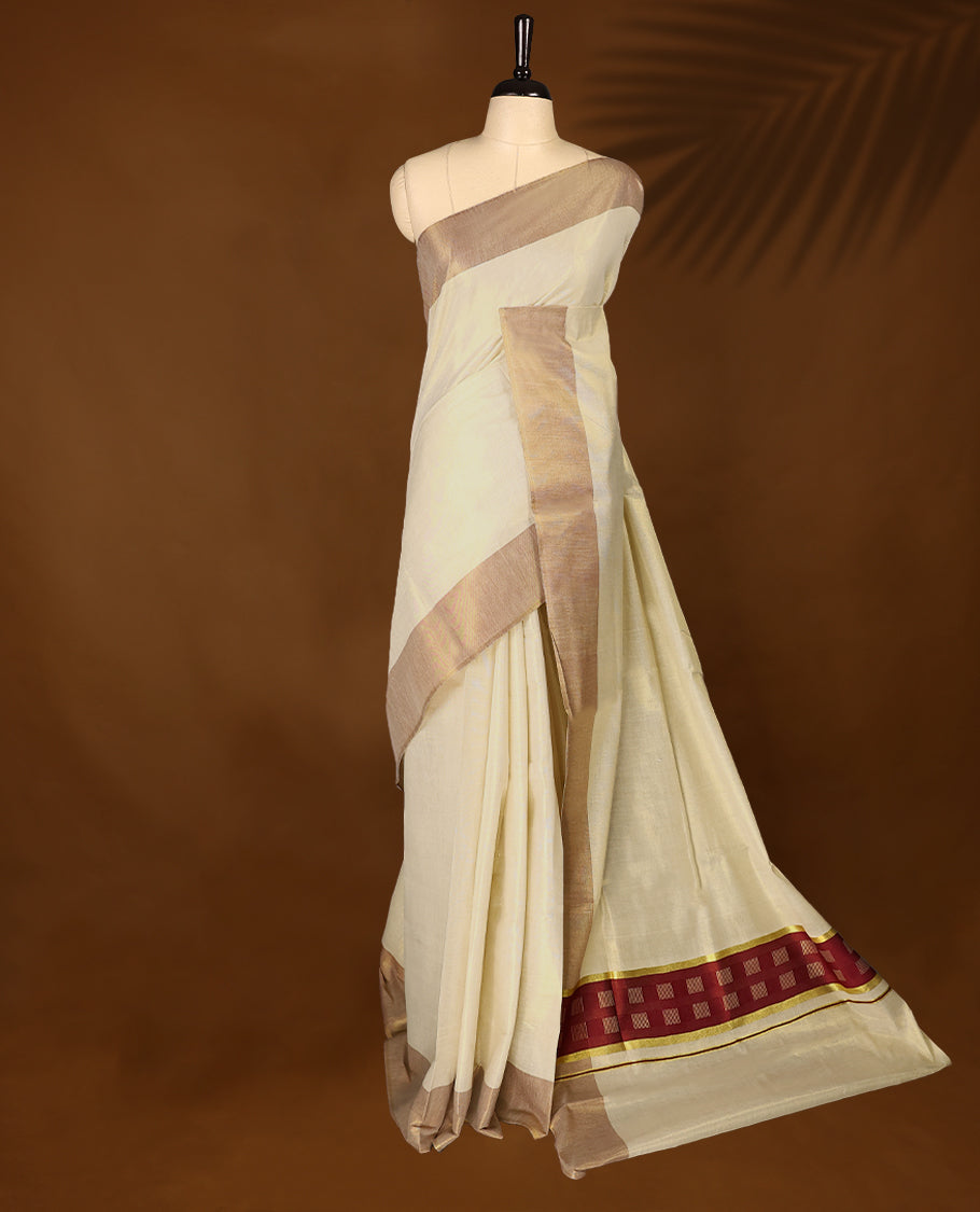 Elegant light gold Colour soft tissue Kerala saree featuring a plain body, muted Red zari border, and a striking Maroon woven checkered pallu, paired with a matching blouse.