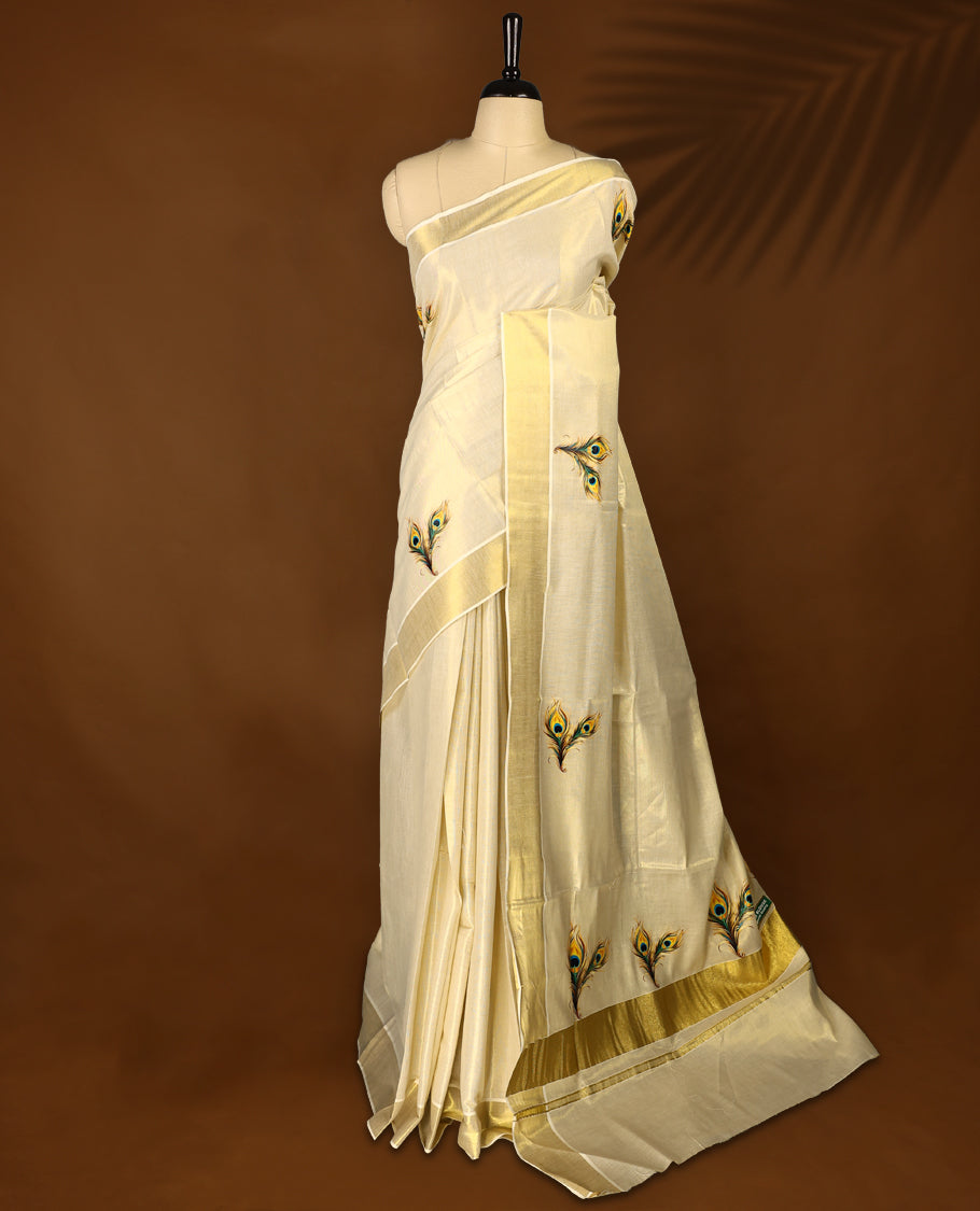 Light Gold colour Tissue Kerala saree featuring Peacock feather prints on body and a beautifully woven Gold Kasavu border, paired with a matching blouse perfect for festive occasions.