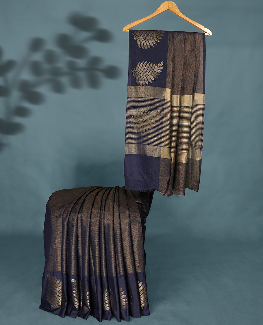 Navy Blue Colour Semi Tussar Silk saree featuring golden zari horizontal lines across the body, adorned with bold Leaf motifs on the border, paired with a matching blouse.
