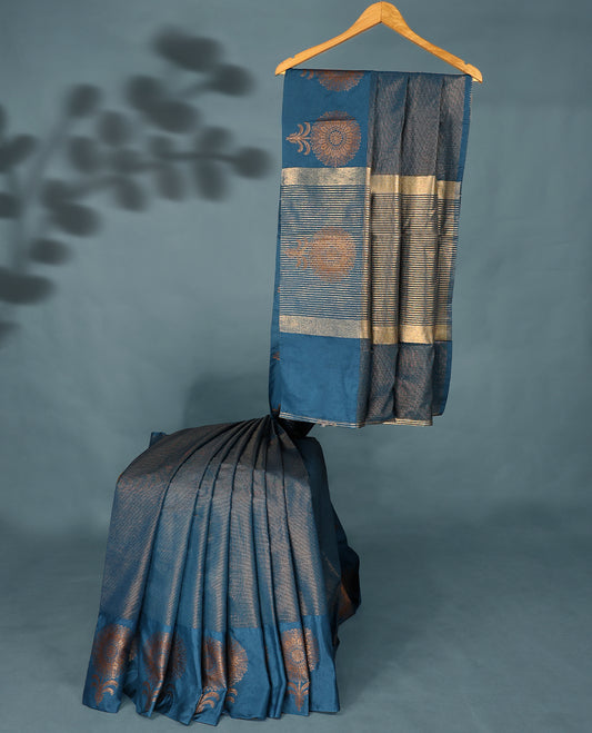 Blue Colour Semi Tussar Silk saree featuring golden zari horizontal lines across the body, adorned with bold floral motifs on the border, paired with a matching blouse.